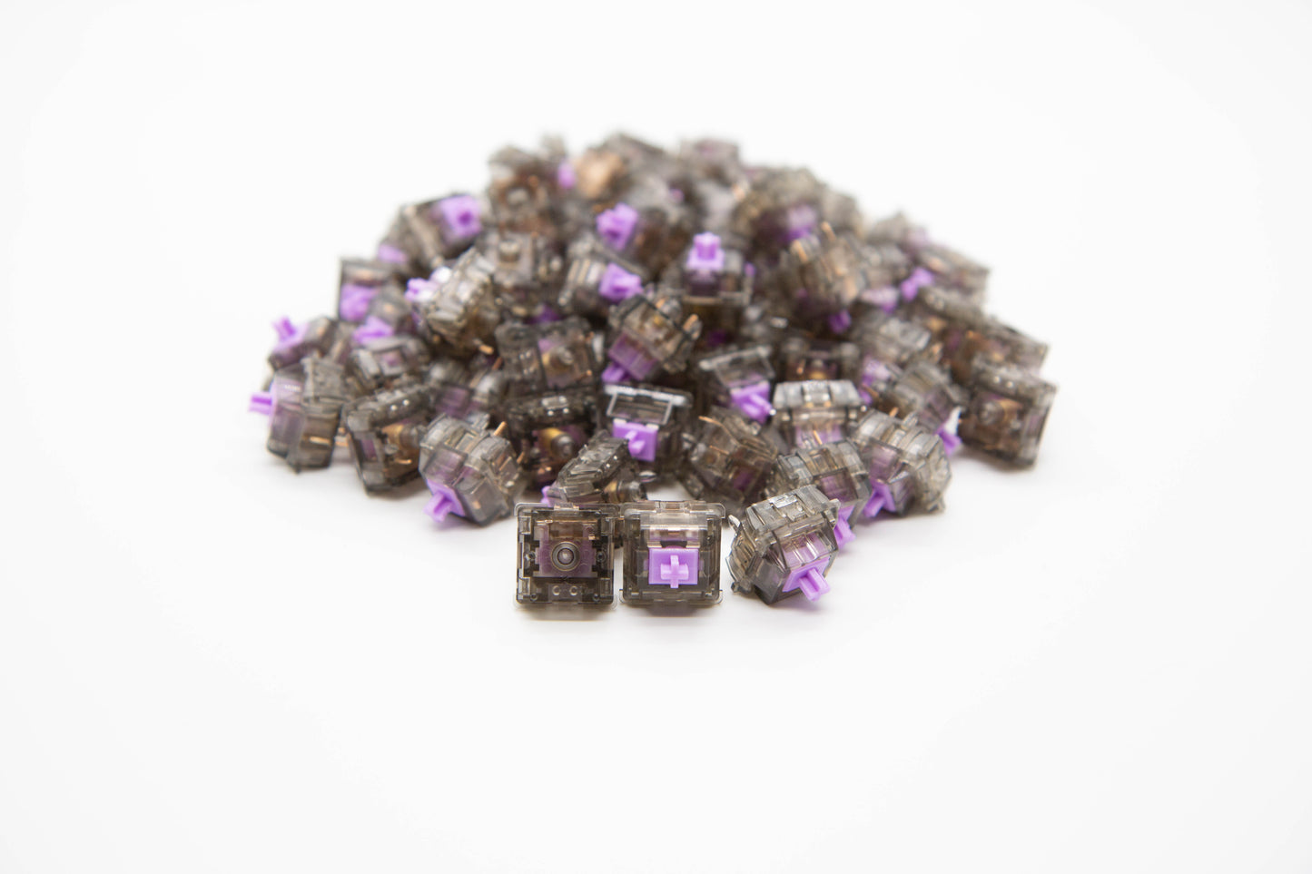 Close-up shot of a pile of Durock Linear-67 g mechanical keyboard switches featuring gray transparent housing and light purple stems