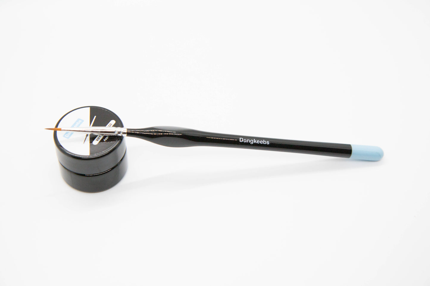 Overhead shot of a Dangkeebs branded size 0 ergonomic lube brush with nylon hairs and dipped blue handle tip over a Dangkeebs branded Krytox 205G0 lube