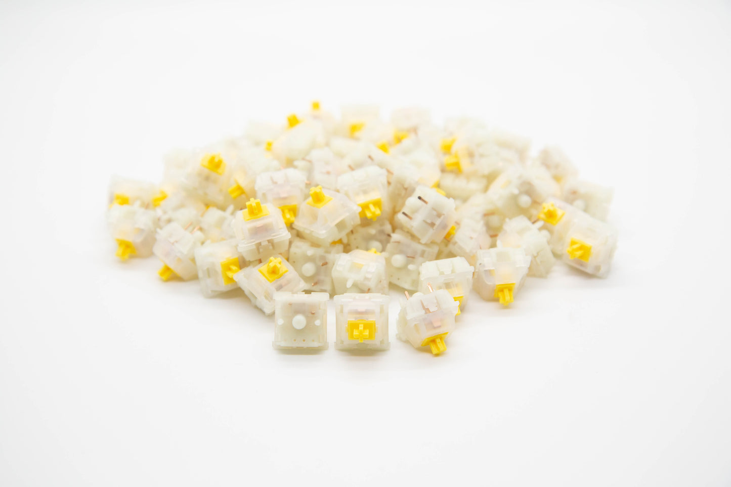 Close-up shot of a pile of Gateron Milky Green mechanical keyboard switches featuring white housing and yellow stems