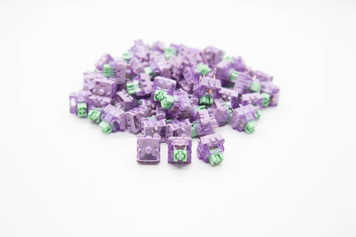 Close-up shot of a pile of Lupine mechanical keyboard switches featuring light purple housing and teal stems
