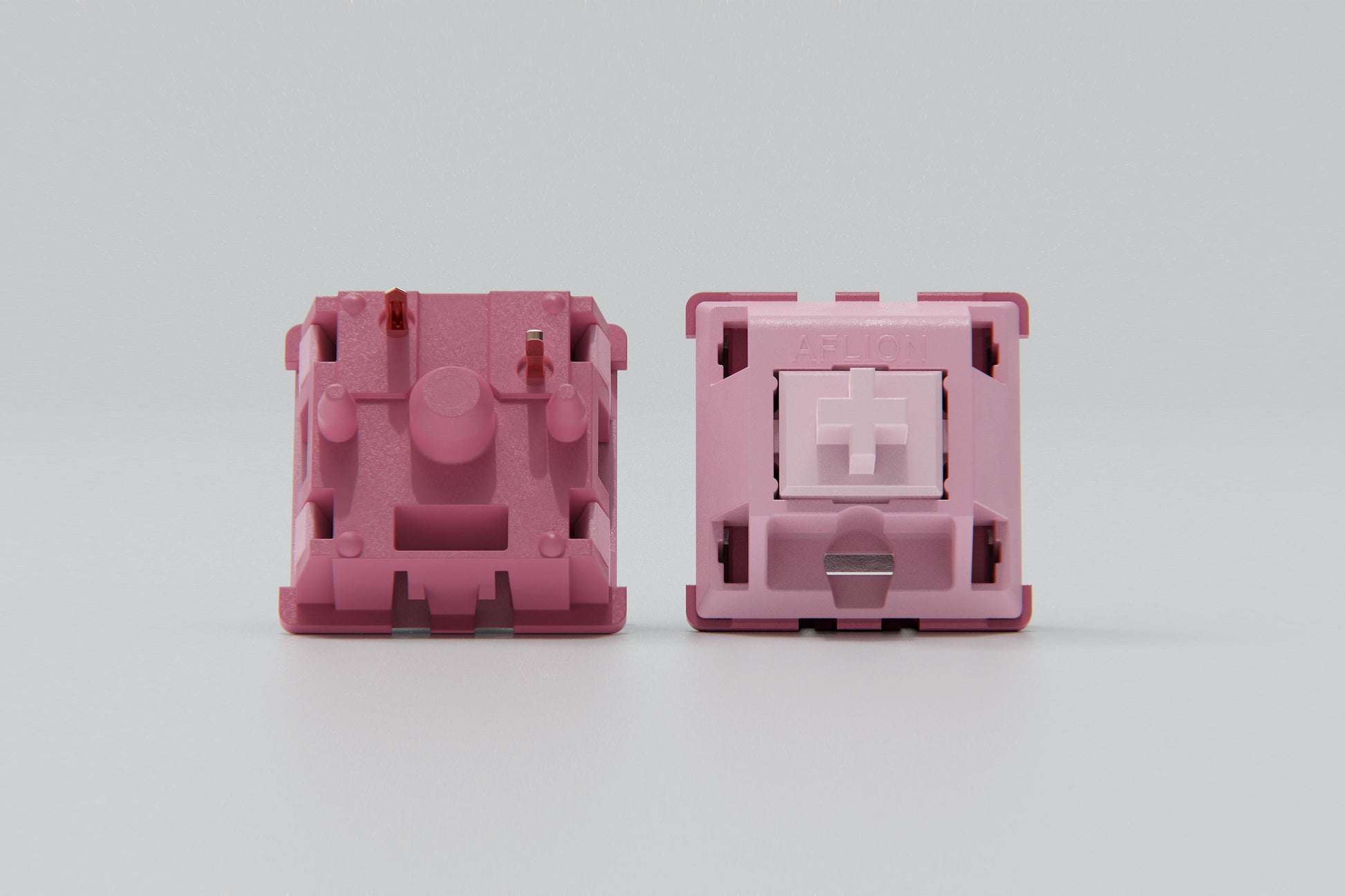 Close-up shot of the top and bottom view of Blush - Linear mechanical keyboard switches featuring dark and light pink housing and light pink stems