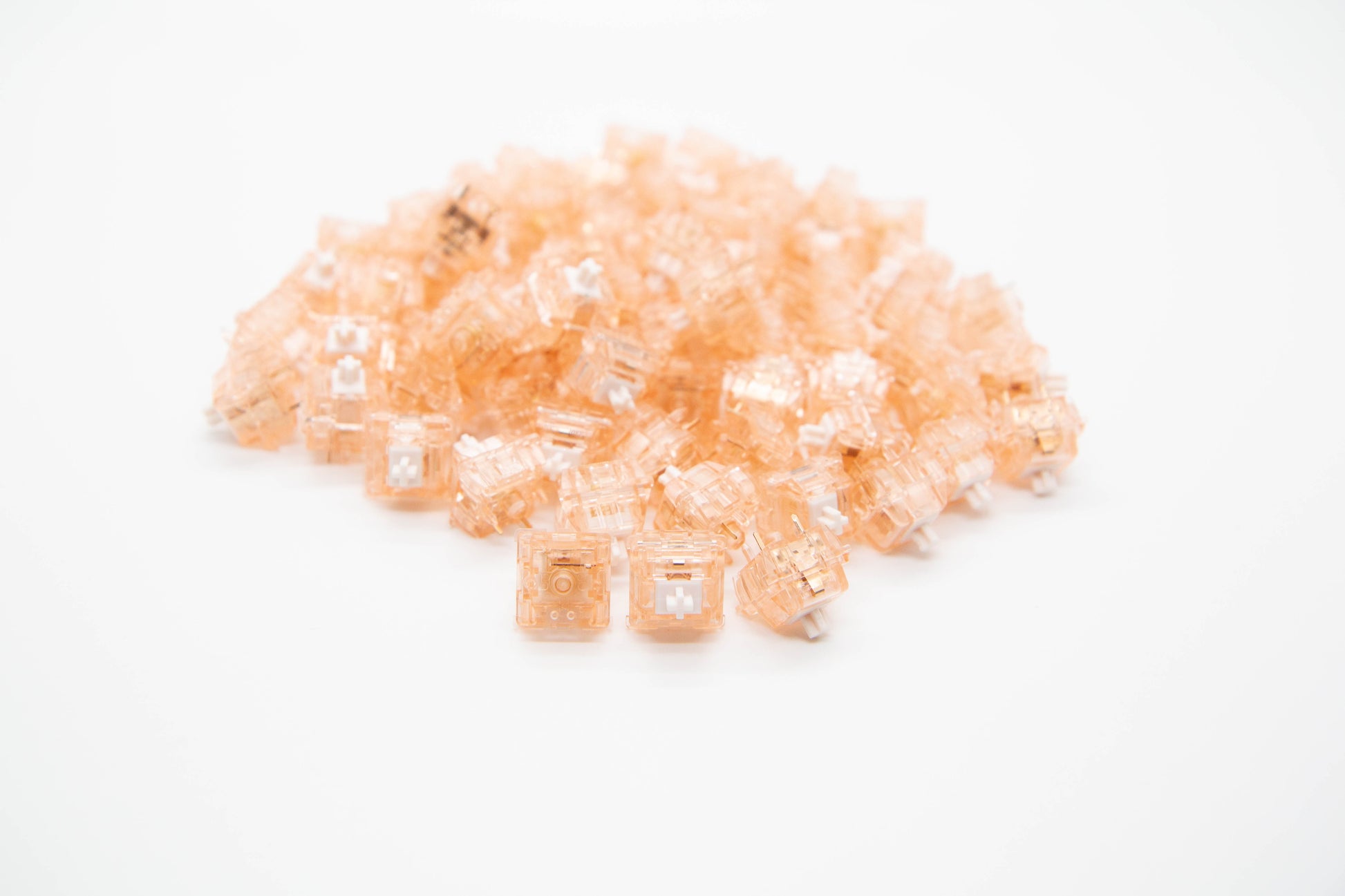 Close-up shot of a pile of Quartz mechanical keyboard switches featuring tan transparent housing and white stems