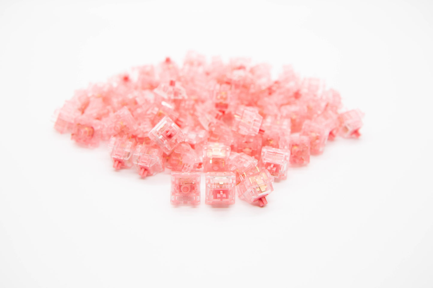 Close-up shot of a pile of Strawberry mechanical keyboard switches featuring pink transparent housing and pink stems