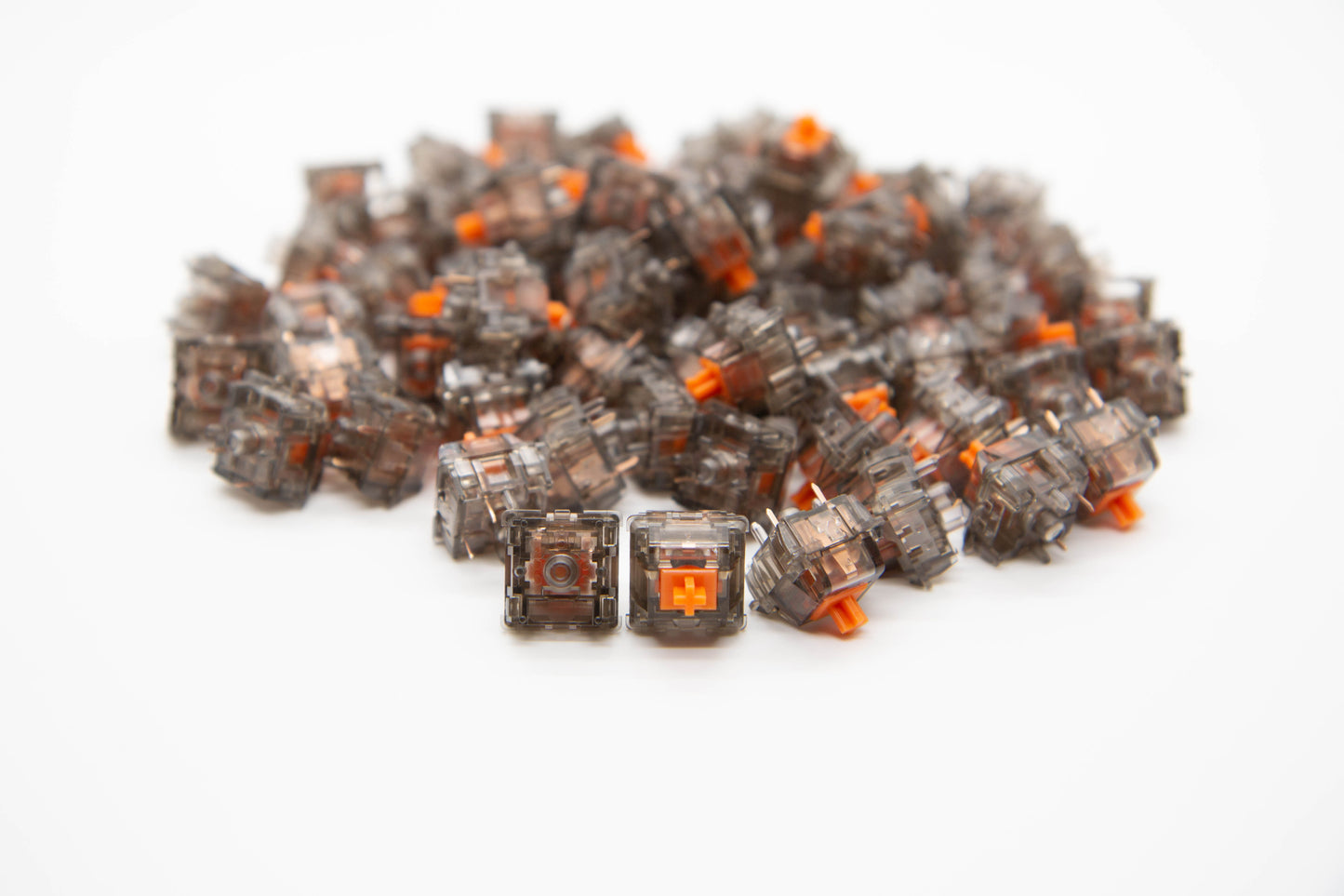 Close-up shot of a pile of Dusk Panda-Tactile mechanical keyboard switches featuring gray transparent housing and orange stems