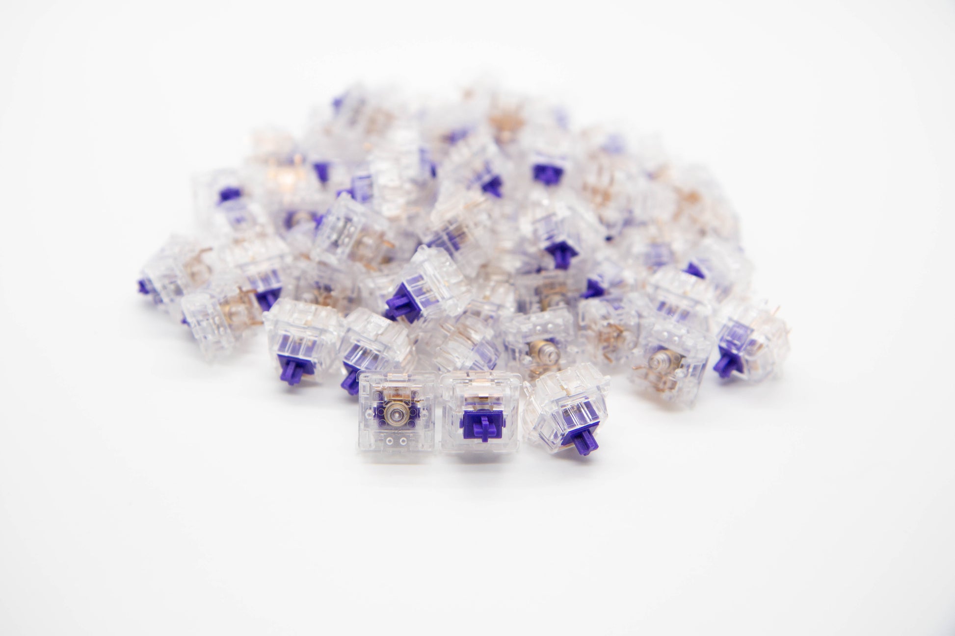 Close-up shot of a pile of Medium Tactile mechanical keyboard switches featuring transparent housing and dark purple stems