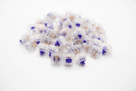 Close-up shot of a pile of Medium Tactile mechanical keyboard switches featuring transparent housing and dark purple stems