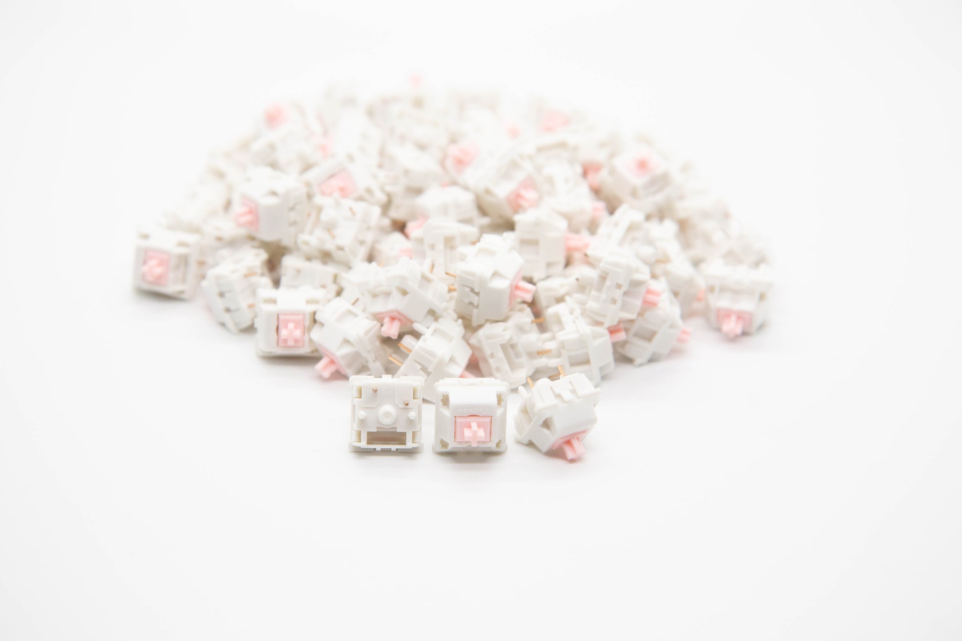 Close-up shot of a pile of Strawberry Milk - Linear themed mechanical keyboard switches featuring white housing and light pink stems