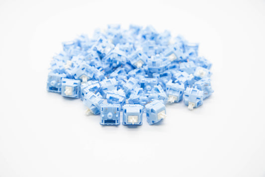 Close up shot of a pile of Blue Velvet Linear themed mechanical keyboard switches featuring white stems and baby blue housing