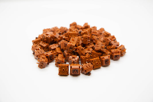 Close-up shot of a pile of Gateron Cap-Brown mechanical keyboard switches featuring brown housing and brown stems