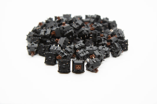 Close up shot of a pile of Cherry Hyperglide Brown mechanical keyboard switches featuring black housing and brown stems