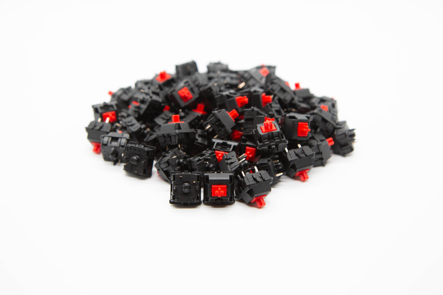 Close up shot of a pile of Cherry Red mechanical keyboard switches featuring black housing and red stems