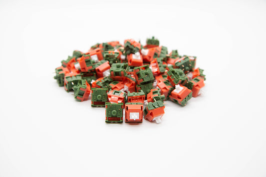 Close-up shot of a pile of TTC Watermelon Milkshake mechanical keyboard switches featuring green and red housing and white stems