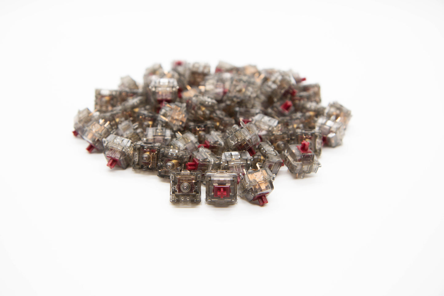 Close-up shot of a pile of Light Tactile mechanical keyboard switches featuring gray transparent housing and dark red stems