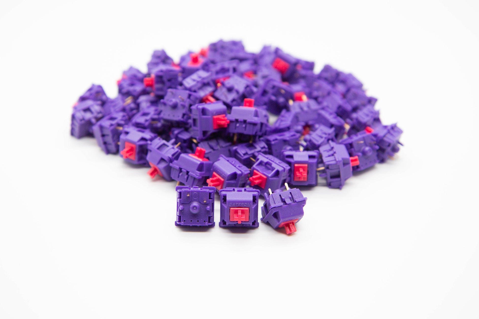 Close-up shot of a pile of KBDFans x MITO x Gateron Laser - 70g mechanical keyboard switches featuring purple housing and red stems