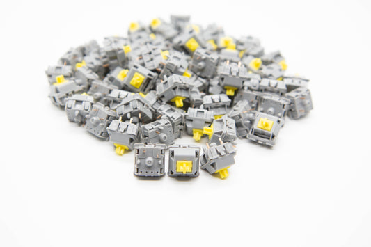 Close-up shot of a pile of Pom T1 mechanical keyboard switches featuring light gray housing and yellow stems
