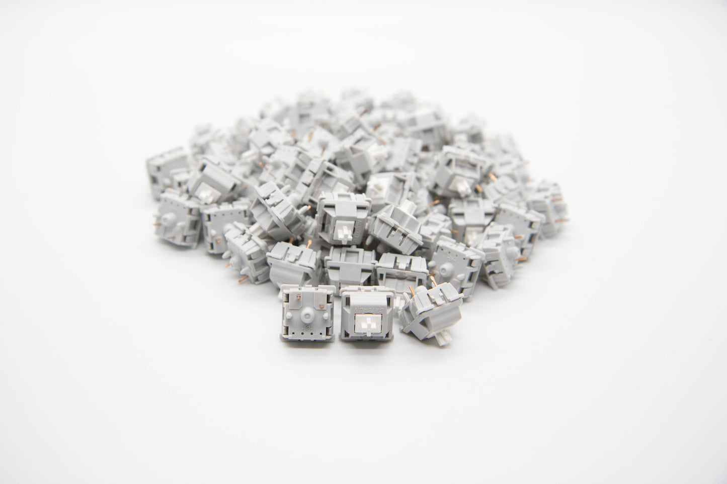 Close-up shot of a pile of Gateron Silver Blizzard mechanical keyboard switches featuring light gray housing and white stems