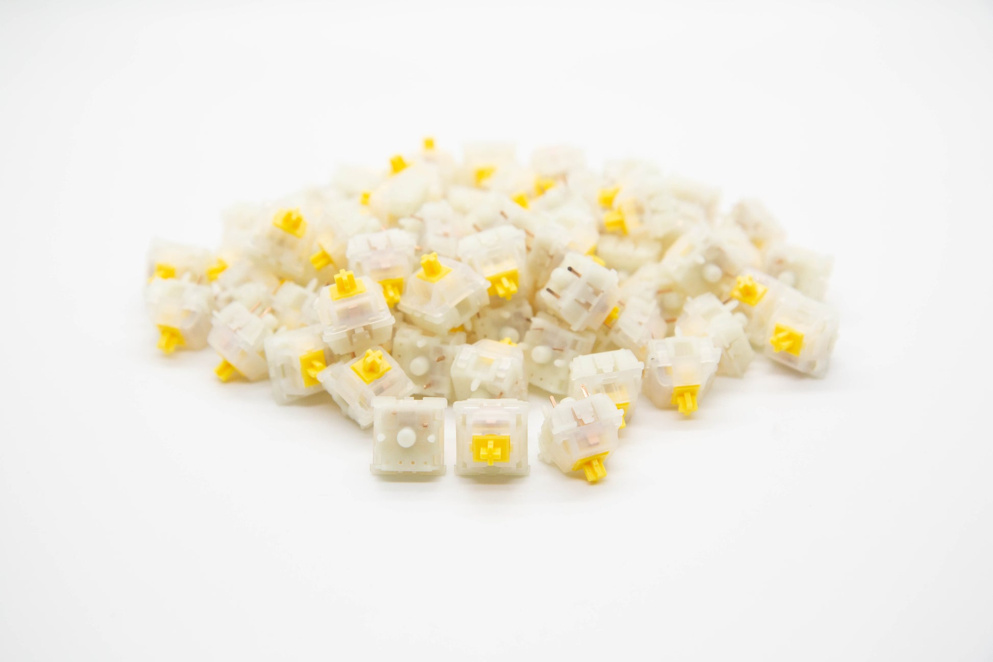 Close-up shot of a pile of Gateron Milky Green mechanical keyboard switches featuring white housing and yellow stems