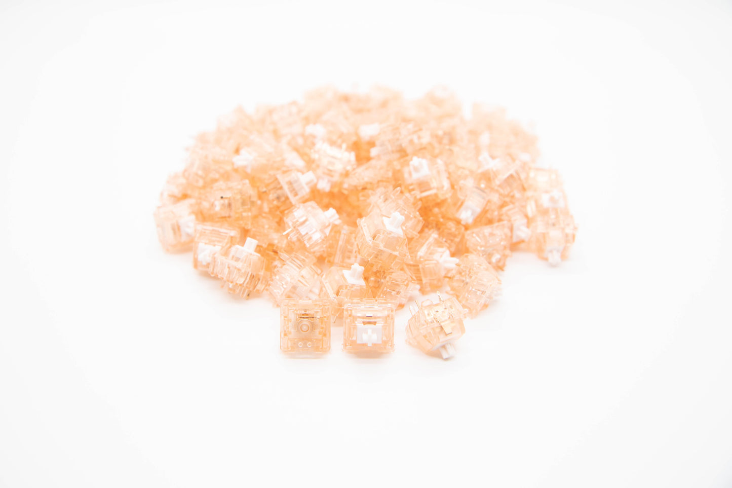 Close-up shot of a pile of Quartz V2 mechanical keyboard switches featuring tan transparent housing and white stems