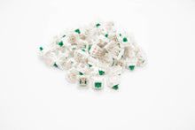 Load image into Gallery viewer, Close up shot of a pile of BBN Linear mechanical keyboard switches featuring white and transparent housing and green stems
