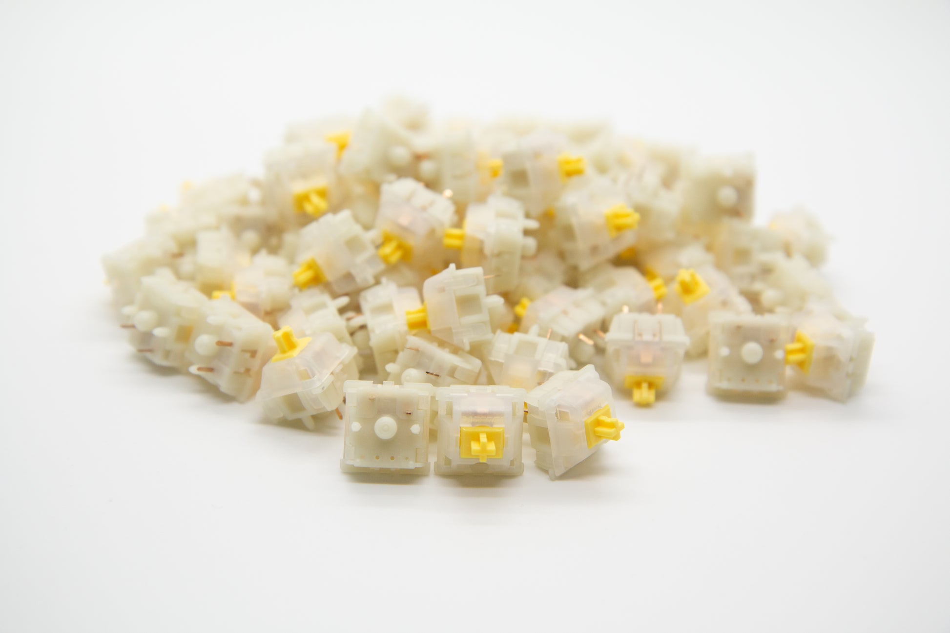 Close-up shot of a pile of Gateron Milky Yellow mechanical keyboard switches featuring white housing and yellow stems