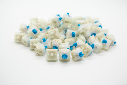 Close-up shot of a pile of Gateron Milky Blue mechanical keyboard switches featuring white housing and blue stems
