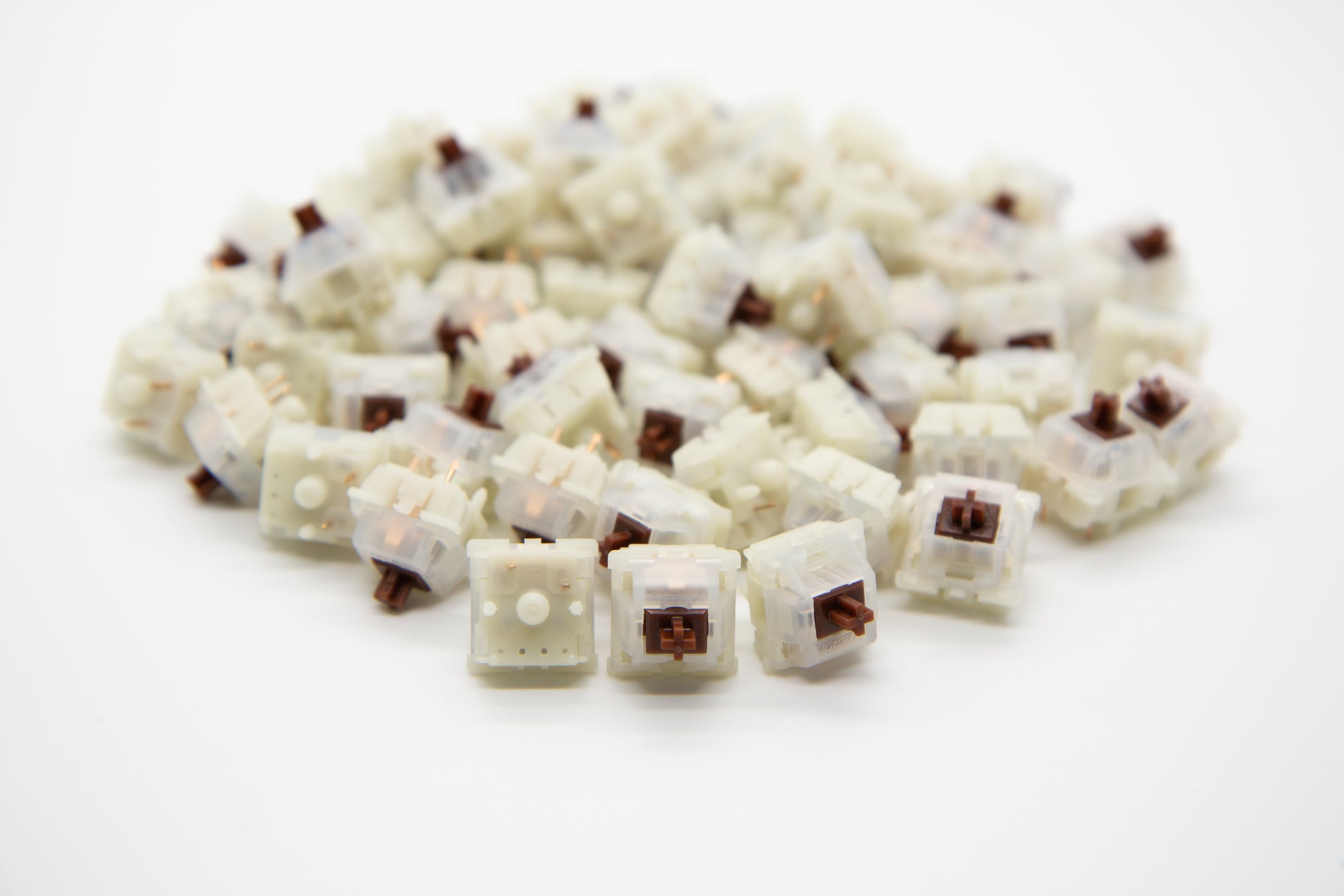 Close-up shot of a pile of Gateron Milky Brown mechanical keyboard switches featuring white housing and brown stems