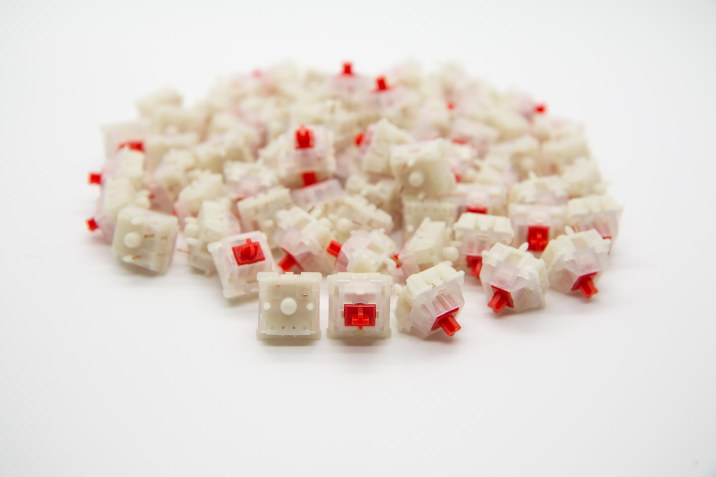 Close-up shot of a pile of Gateron Milky Red mechanical keyboard switches featuring white housing and red stems