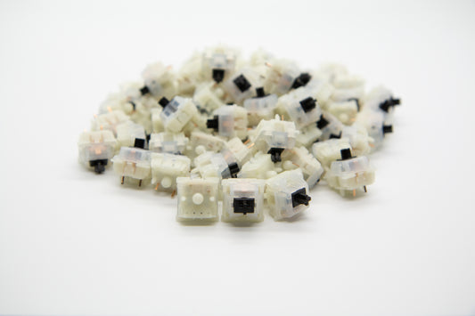 Close-up shot of a pile of Gateron Milky Black mechanical keyboard switches featuring white housing and black stems