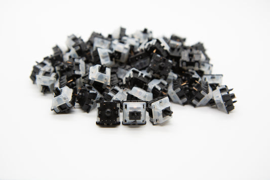 Close-up shot of a pile of Gateron Black mechanical keyboard switches featuring black and white housing and black stems