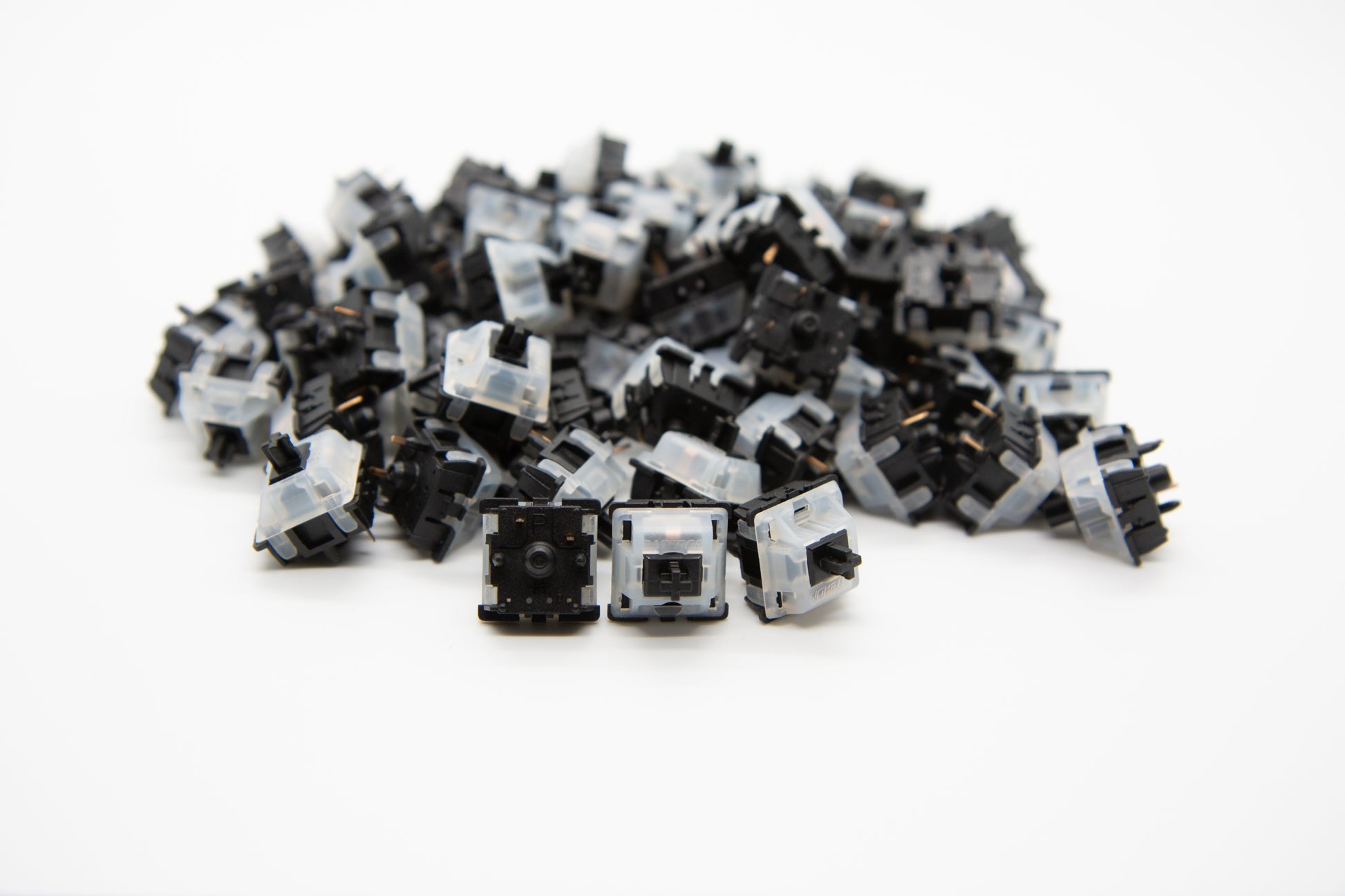 Close-up shot of a pile of Gateron Black mechanical keyboard switches featuring black and white housing and black stems