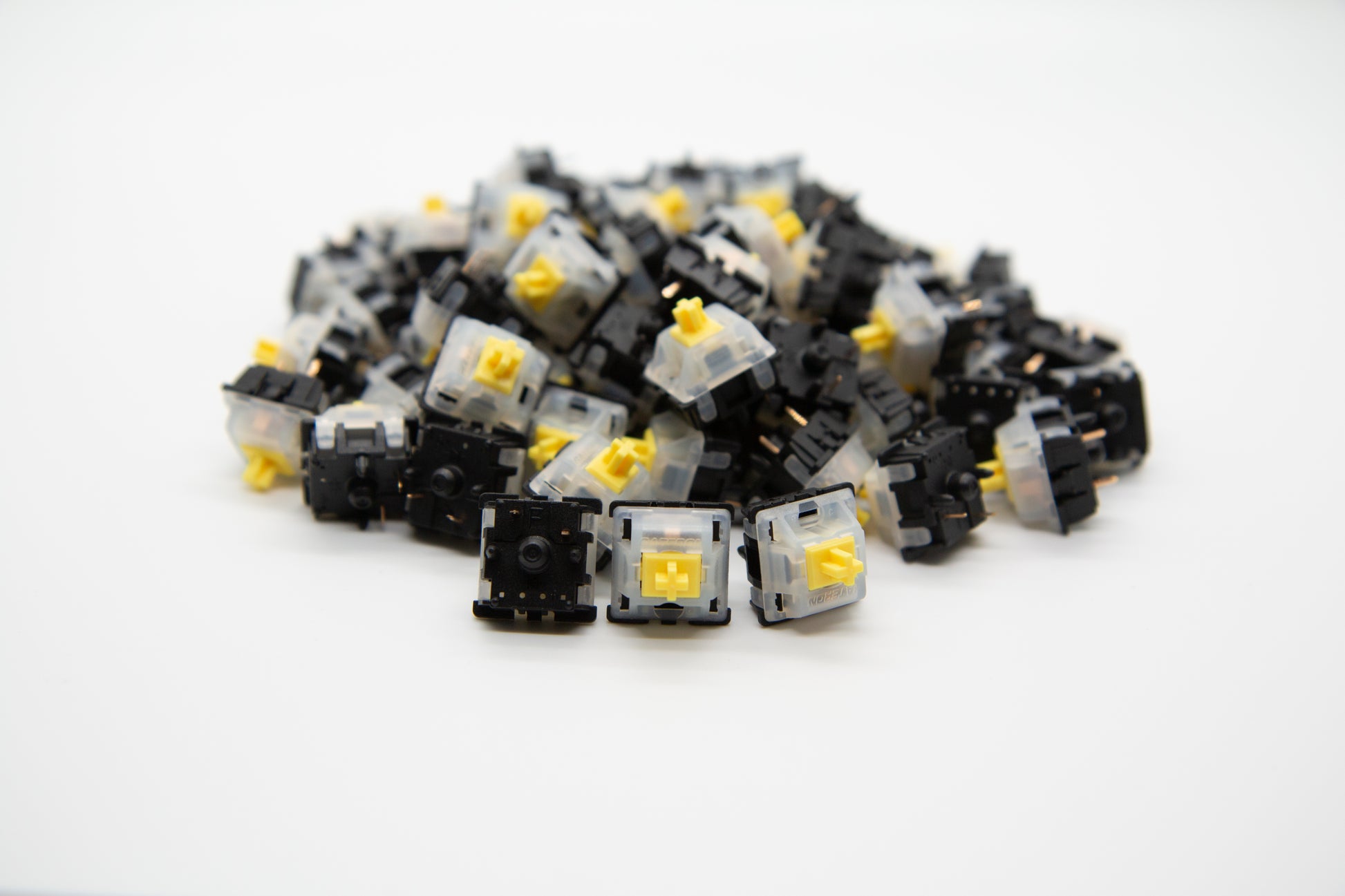 Close-up shot of a pile of Gateron Yellow mechanical keyboard switches featuring black and white housing and yellow stems