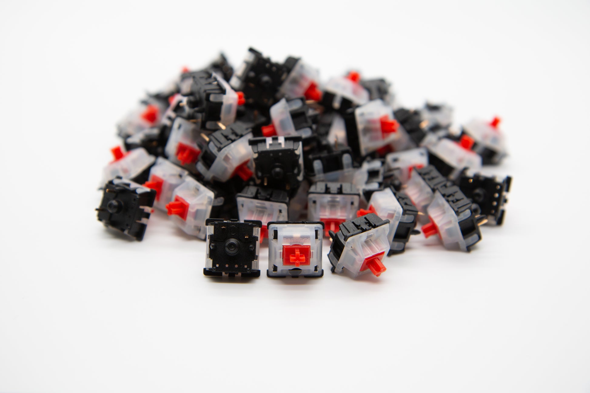 Close-up shot of a pile of Gateron Red mechanical keyboard switches featuring black and white housing and red stems