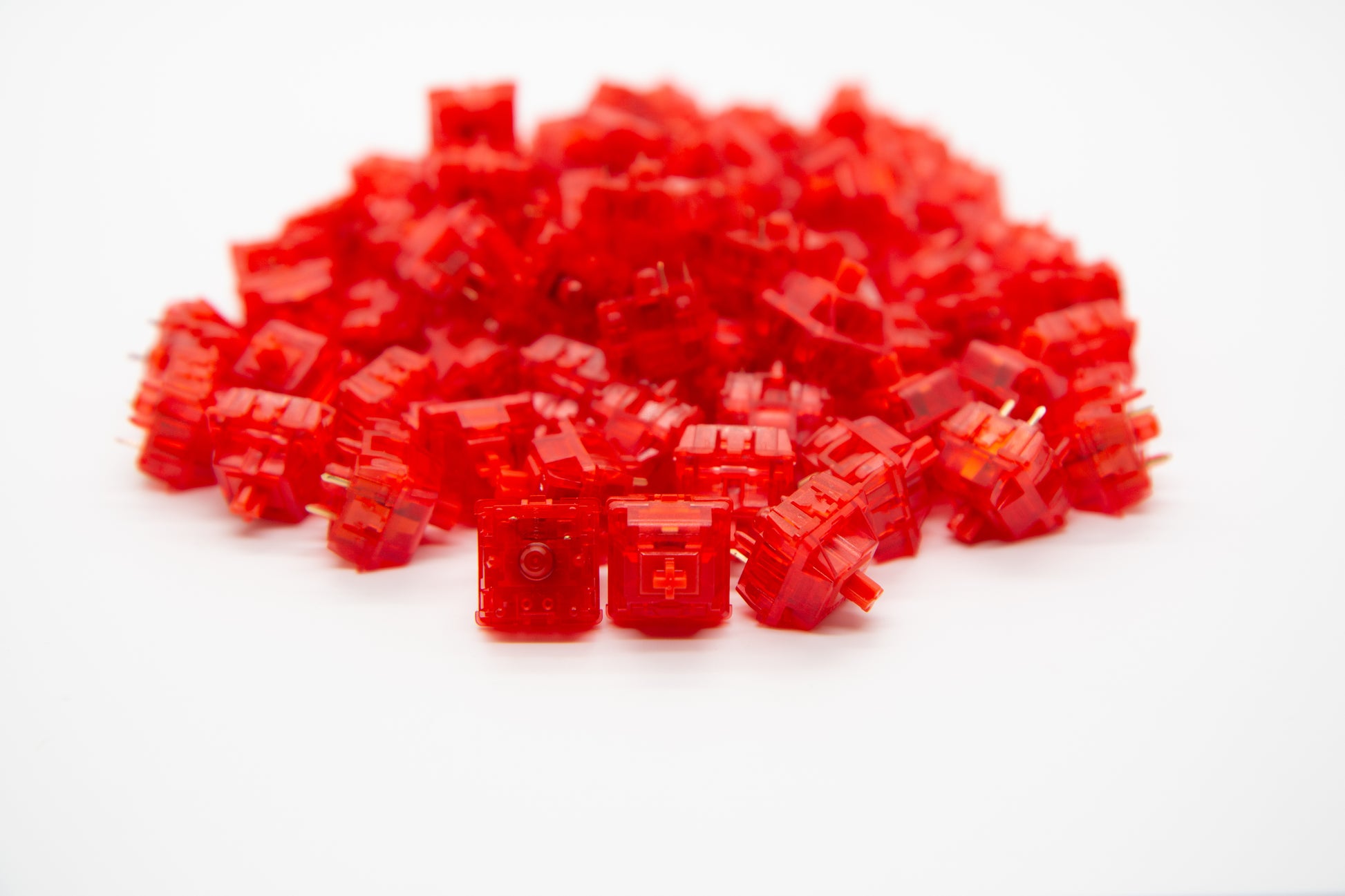 Close-up shot of a pile of Gateron Red Ink V2 mechanical keyboard switches featuring red housing and red stems