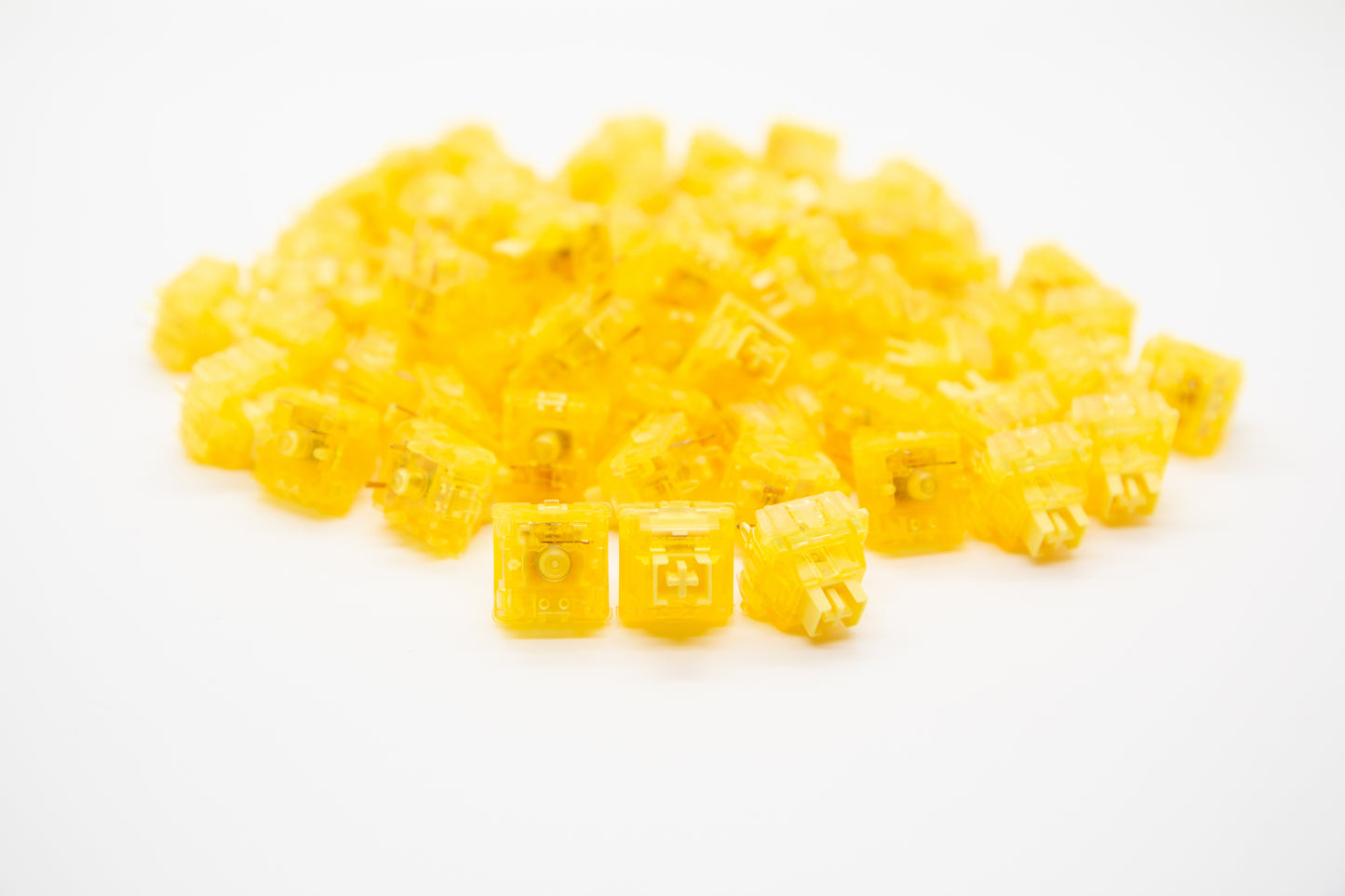 Close-up shot of a pile of Gateron Yellow Ink V2 mechanical keyboard switches featuring yellow housing and yellow stems