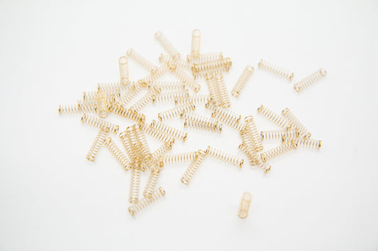 Close-up shot of a single 62g dual stage gold plated mechanical keyboard spring on a grey background