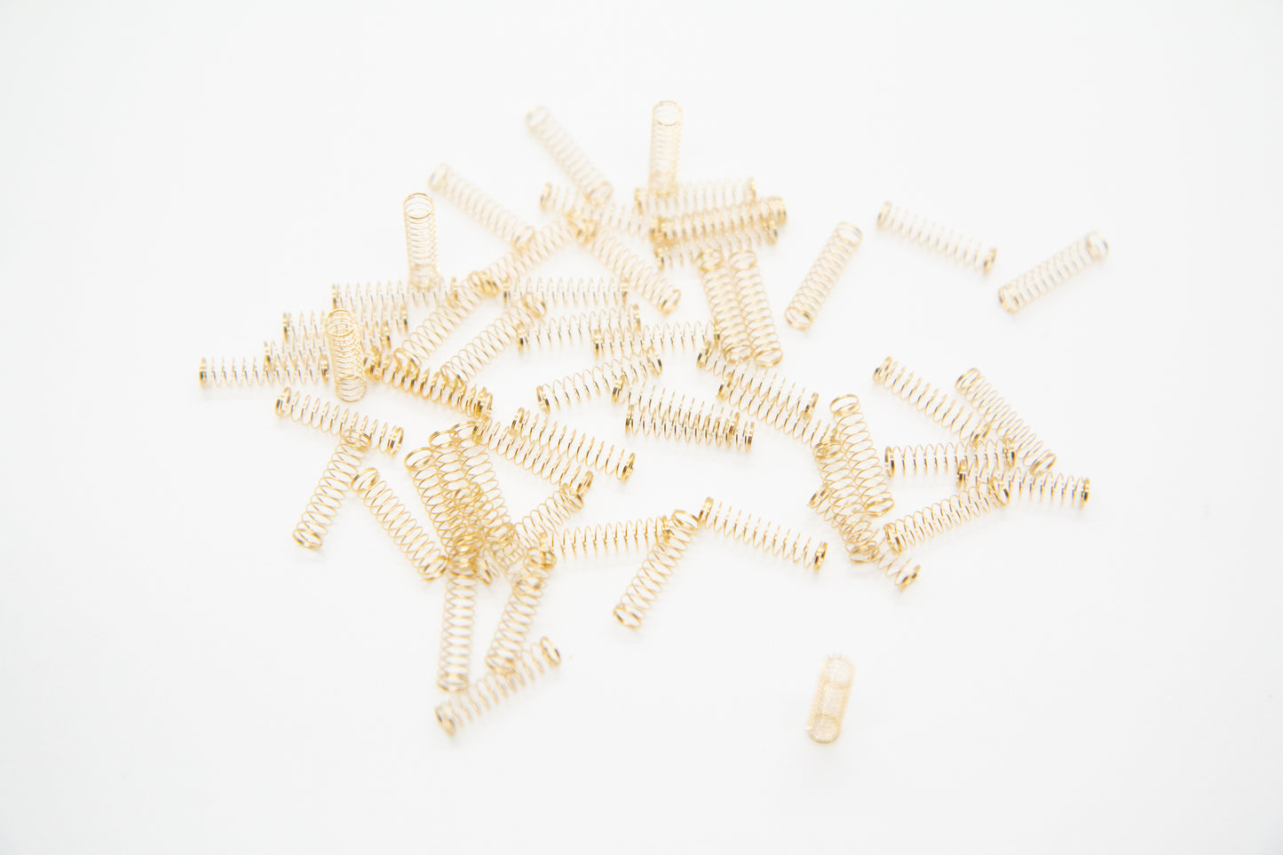 Close-up shot of a single 67g dual stage gold plated mechanical keyboard spring on a grey background