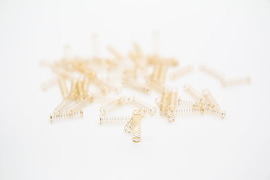 Close-up shot of a single 65g dual stage gold plated mechanical keyboard spring on a grey background