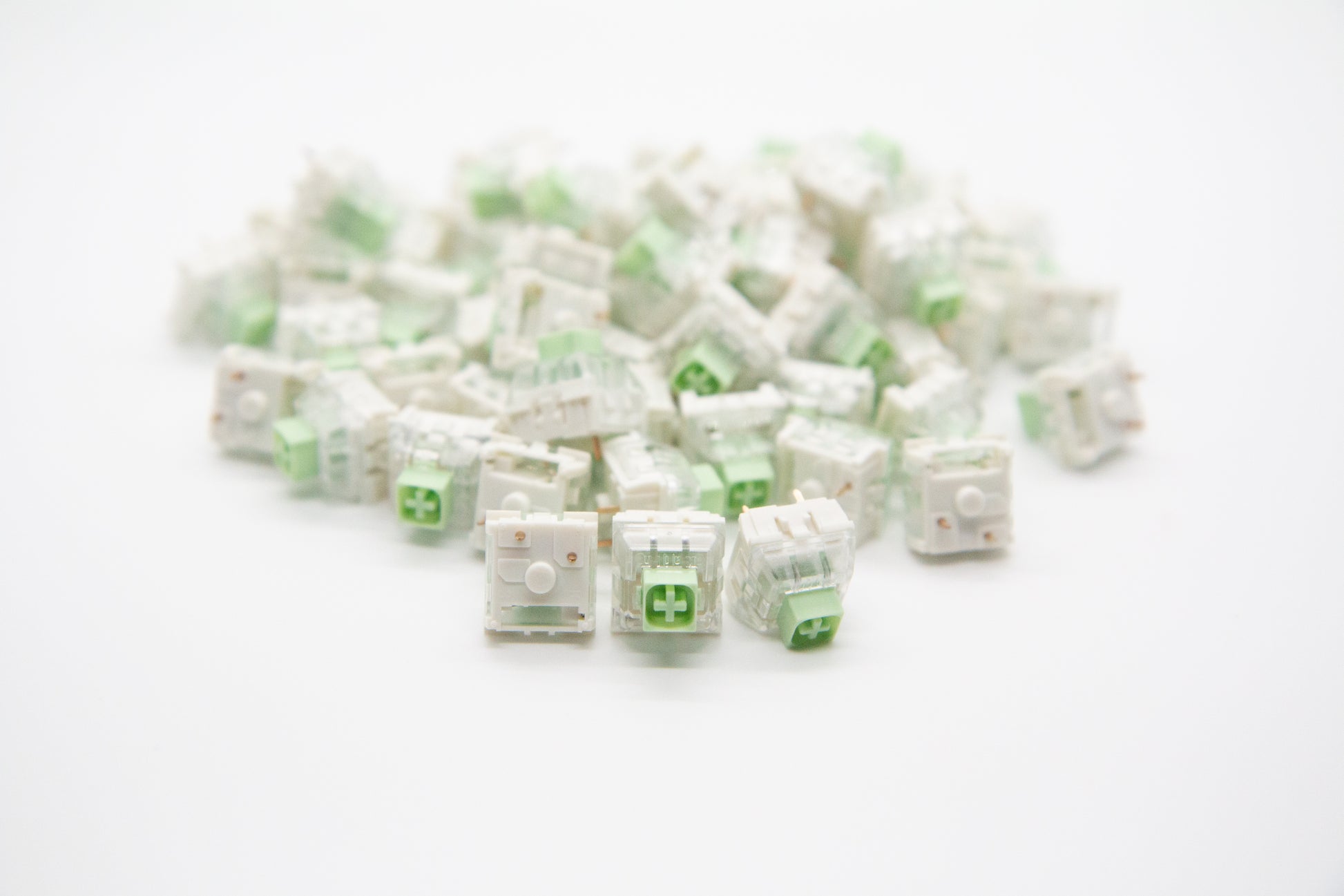 Close-up shot of a pile of Novelkeys x Kailh Box Jade mechanical keyboard switches featuring white and transparent housing and light green stems