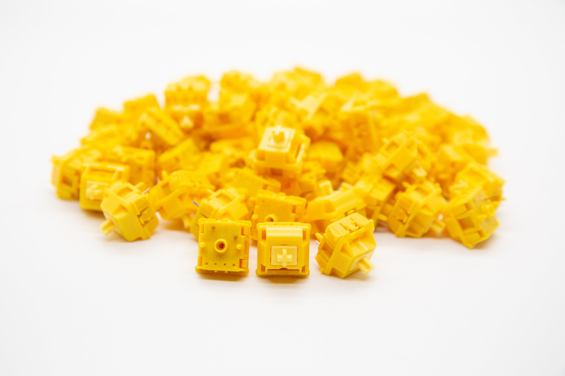 Close-up shot of a pile of Gateron Cap-Yellow mechanical keyboard switches featuring yellow housing and yellow stems