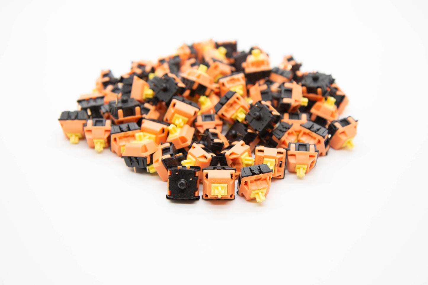 Close up shot of a pile of Silent Yellow mechanical keyboard switches featuring black/orange housing and yellow stems