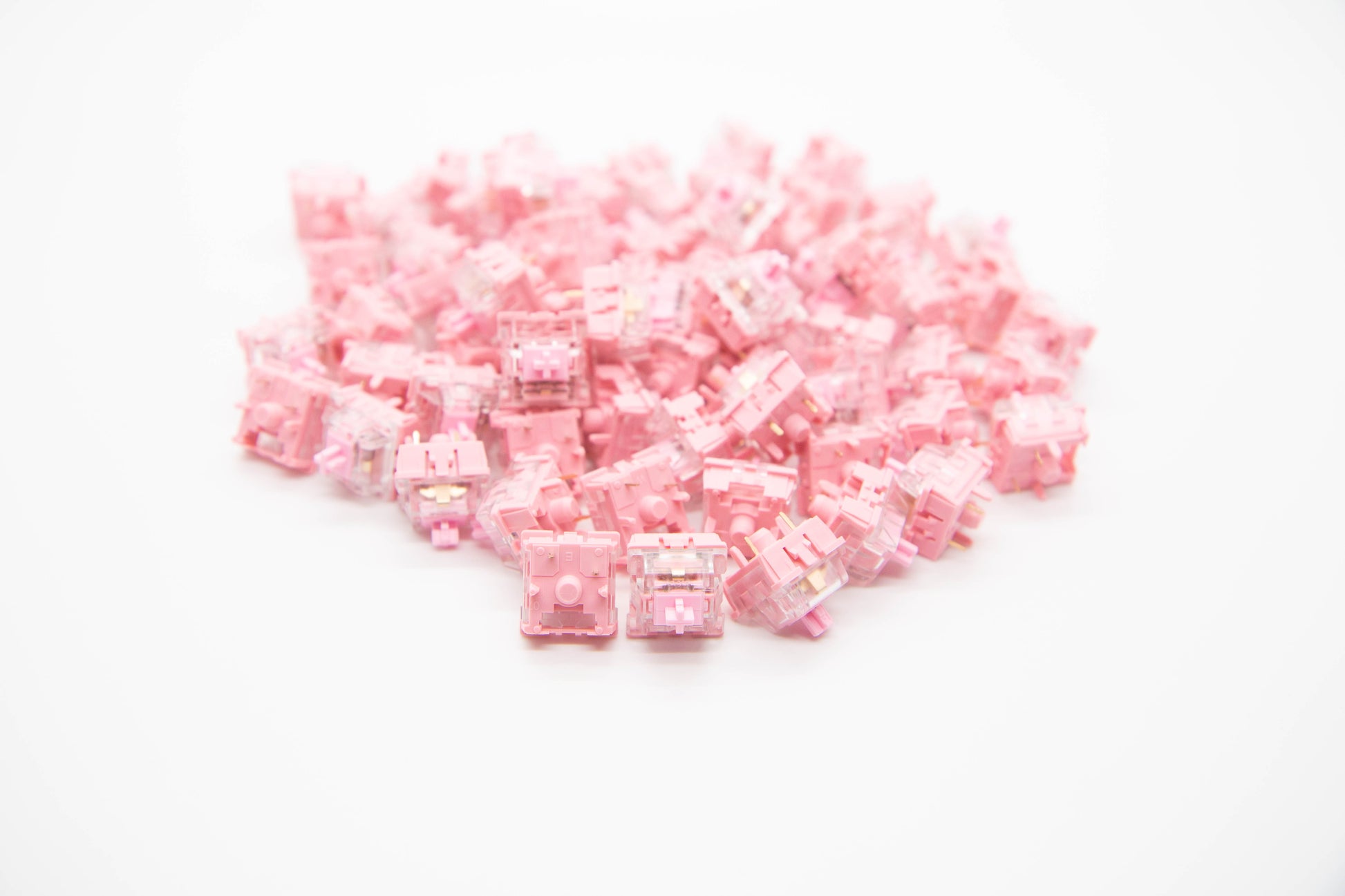 Close-up shot of a pile of KTT Rose mechanical keyboard switches featuring light pink and transparent housing and stems