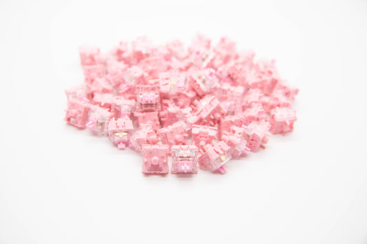 Close-up shot of a pile of KTT Rose mechanical keyboard switches featuring light pink and transparent housing and stems