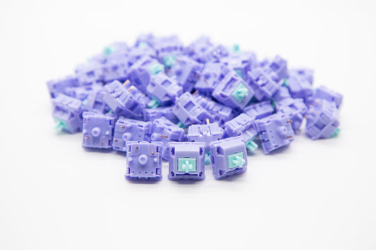Close-up shot of a pile of HaluHalo mechanical keyboard switches featuring light purple housing and teal stems