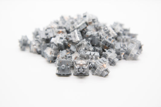 Close-up shot of a pile of Gateron Slate mechanical keyboard switches featuring gray and clear housing and gray stems