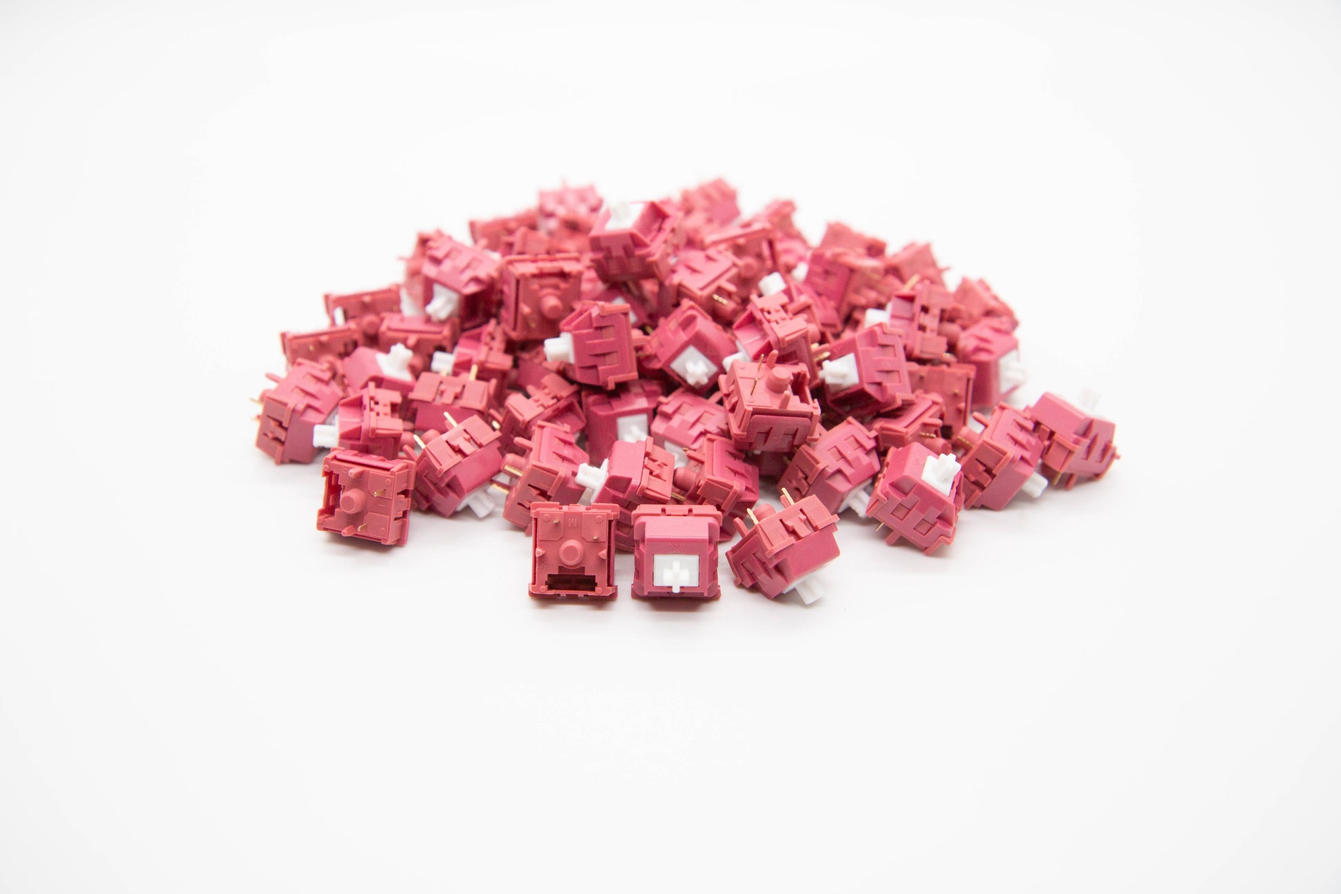 Close-up shot of a pile of KTT Grapefruit mechanical keyboard switches featuring maroon housing and white stems