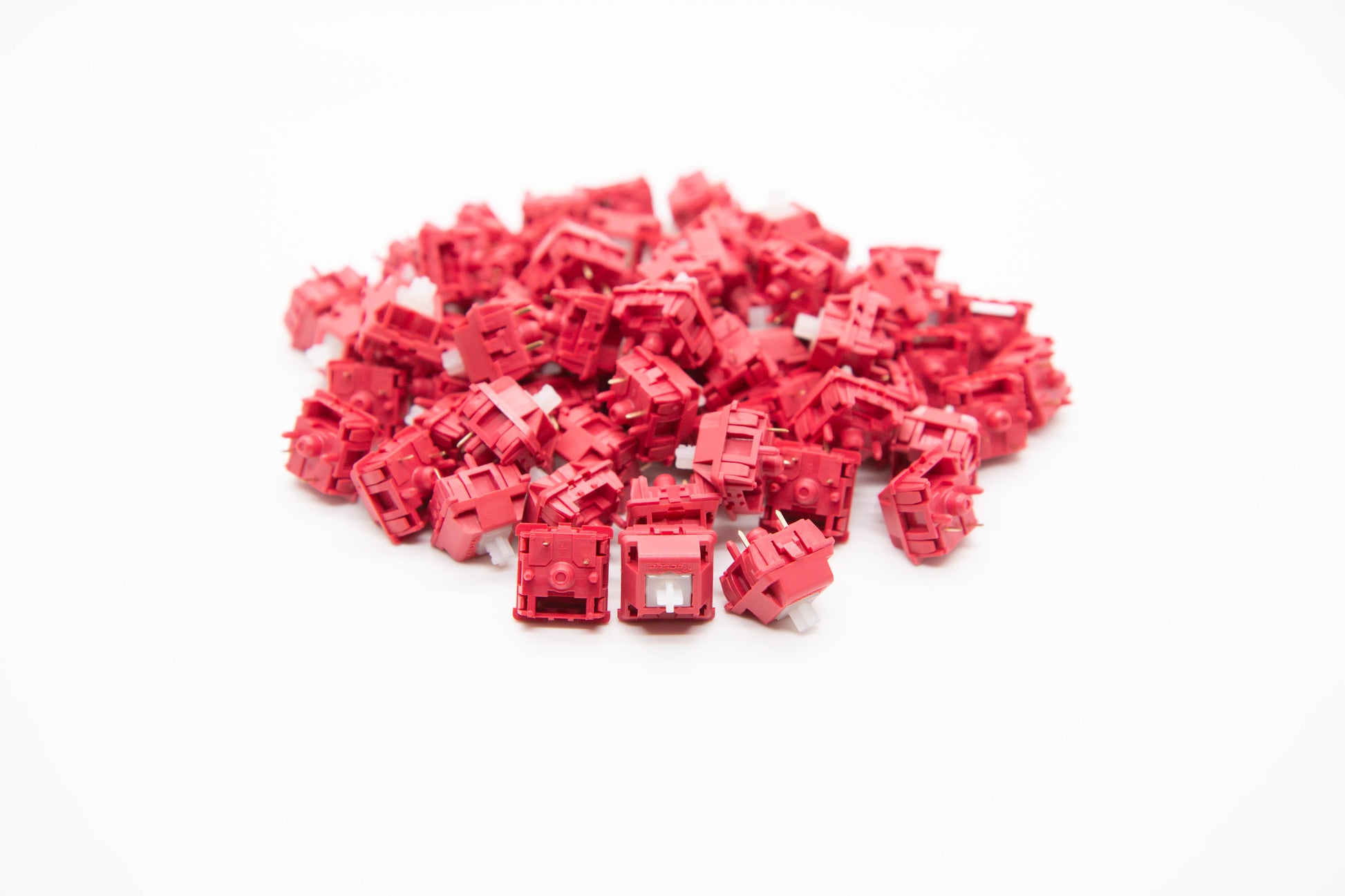Close-up shot of a pile of Lychhe UHMWPE - Tactile mechanical keyboard switches featuring bold red housing and clear stems