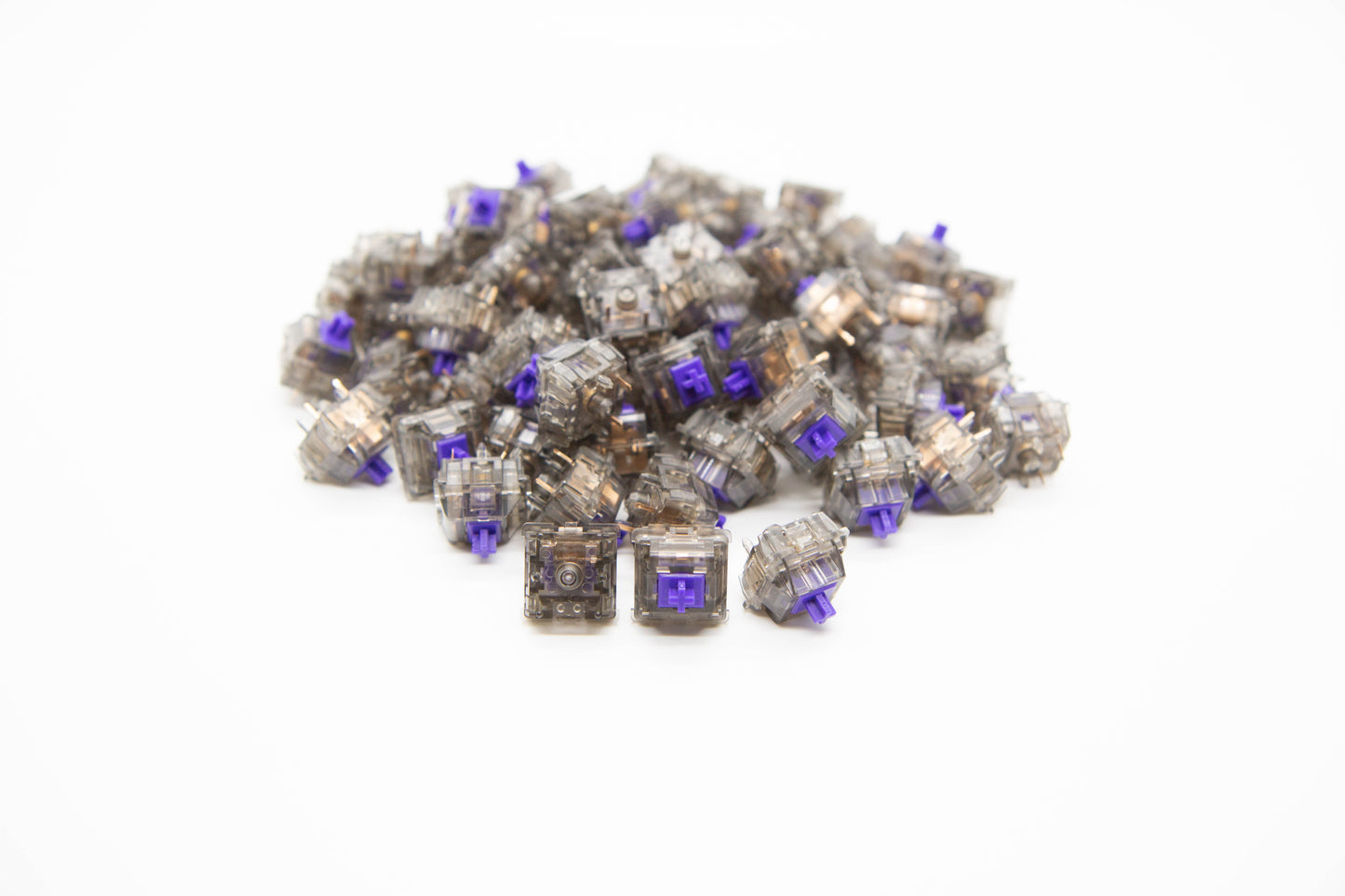 Close-up shot of a pile of Twilight mechanical keyboard switches featuring gray transparent housing and purple stems