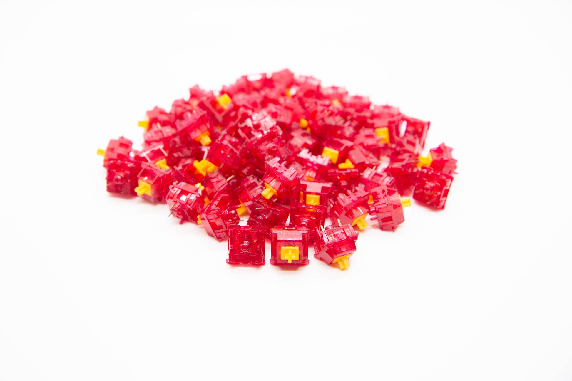Close-up shot of a pile of Tecsee Ruby mechanical keyboard switches featuring bright red transparent housing and yellow stems