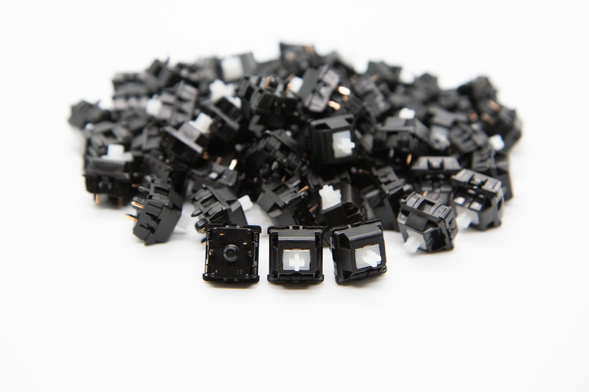 Close-up shot of a pile of Pom Linear mechanical keyboard switches featuring black housing and clear, white stems