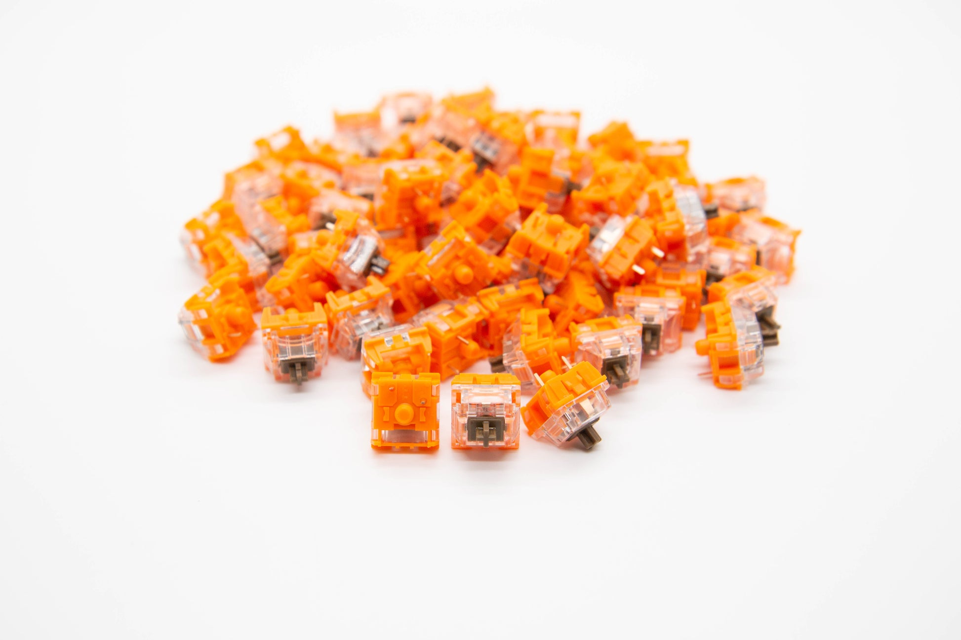 Close-up shot of a pile of TTC Golden Brown mechanical keyboard switches featuring orange and transparent housing and brown stems